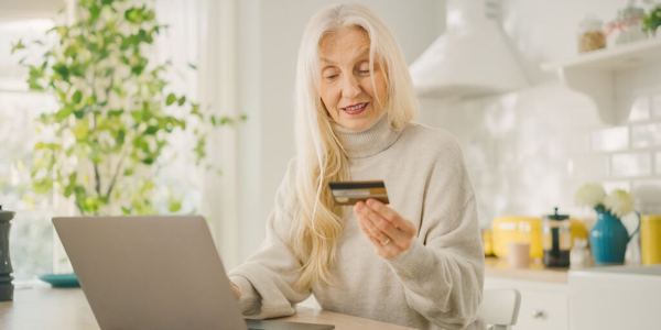 vrouw-lang-grijs-haar-laptop-thuis-bankkaart-600x300